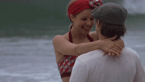 A Man And A Woman Are Hugging Each Other On The Beach GIF