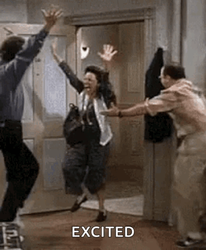 A Man And A Woman Are Jumping In The Air In A Room With Their Arms In The Air . GIF