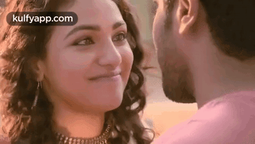 A Man And A Woman Are Kissing Each Other And The Woman Is Smiling . GIF