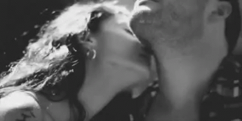 A Man And A Woman Are Kissing Each Other In A Black And White Photo . GIF
