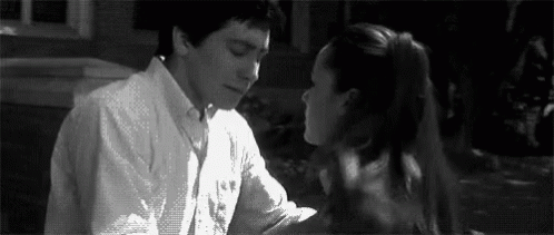 A Man And A Woman Are Kissing Each Other In A Black And White Photo . GIF