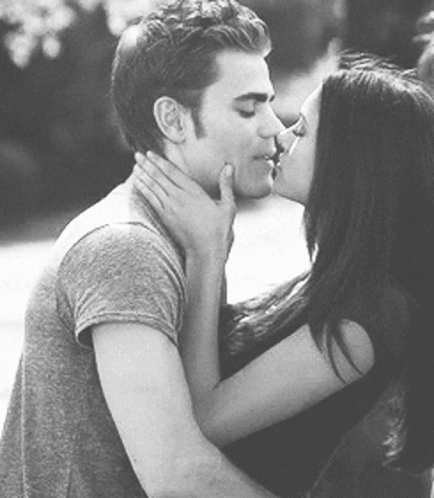 A Man And A Woman Are Kissing Each Other In A Black And White Photo . GIF