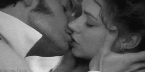 A Man And A Woman Are Kissing Each Other In A Black And White Photo . GIF