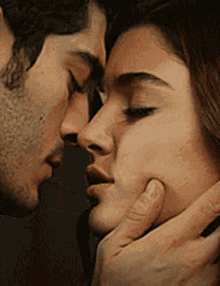 A Man And A Woman Are Kissing Each Other In A Close Up Of Their Faces . GIF
