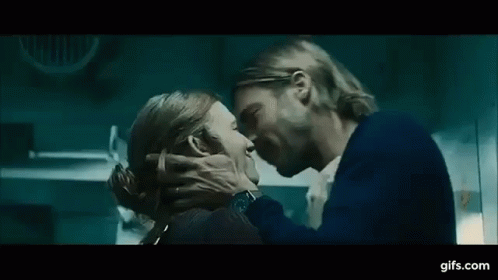 A Man And A Woman Are Kissing Each Other In A Dark Room . GIF