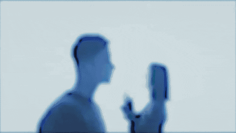 A Man And A Woman Are Kissing Each Other In A Dark Room . GIF