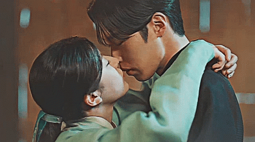 A Man And A Woman Are Kissing Each Other In A Room . GIF
