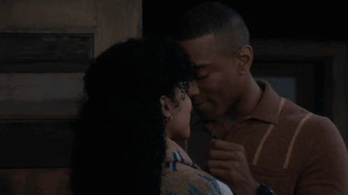 A Man And A Woman Are Kissing Each Other In Front Of A Door . GIF