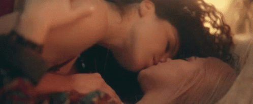 A Man And A Woman Are Kissing Each Other On A Bed . GIF