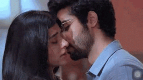 A Man And A Woman Are Kissing Each Other On The Cheek . GIF