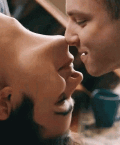 A Man And A Woman Are Kissing Each Other On The Forehead . GIF
