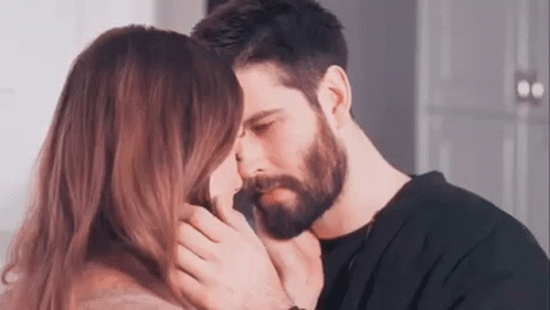 A Man And A Woman Are Kissing Each Other . The Man Has A Beard And The Woman Has Long Hair . GIF