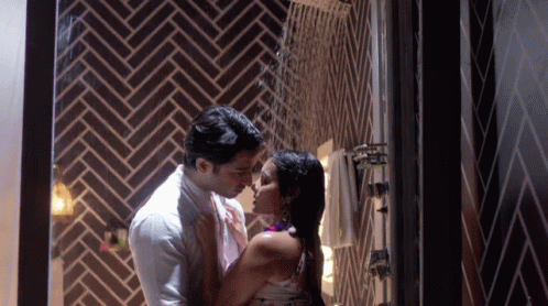 A Man And A Woman Are Kissing In A Bathroom GIF