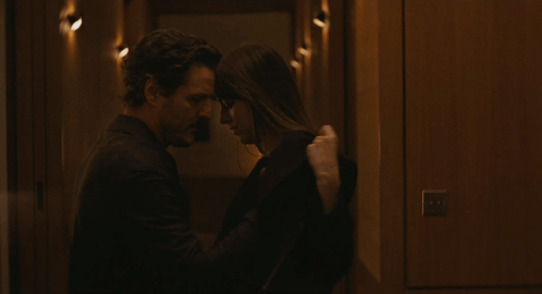 a man and a woman are kissing in a dark hallway