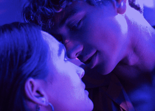 A Man And A Woman Are Kissing In A Dark Room GIF