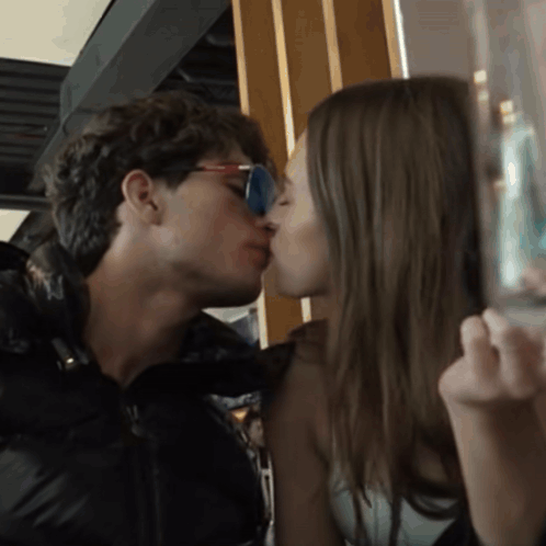 A Man And A Woman Are Kissing In A Dark Room GIF