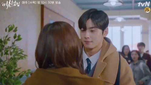 A Man And A Woman Are Kissing In A Hallway . GIF