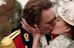 a man and a woman are kissing in a military uniform and hat .