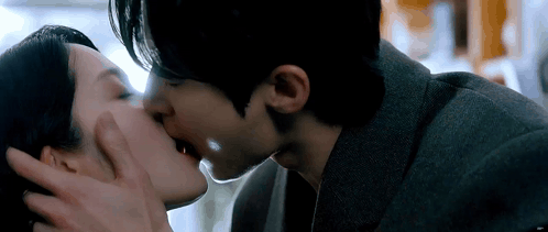 A Man And A Woman Are Kissing In A Room . GIF