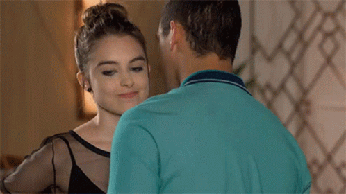 A Man And A Woman Are Kissing In A Room . The Woman Is Wearing A Black Top . GIF