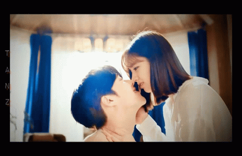 A Man And A Woman Are Kissing In A Room With The Letter T On The Bottom Right GIF