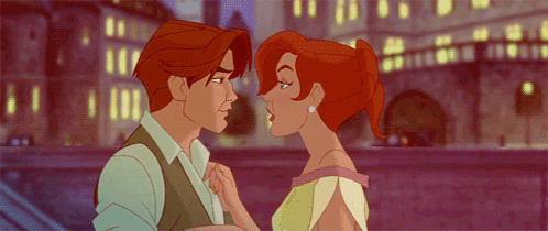 A Man And A Woman Are Kissing In Front Of A Bridge GIF