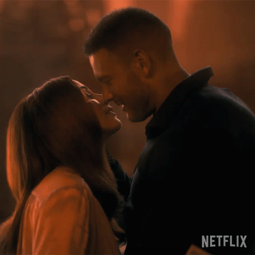 A Man And A Woman Are Kissing In Front Of A Netflix Logo GIF