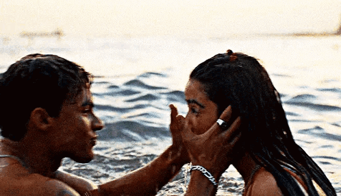 A Man And A Woman Are Kissing In The Ocean . GIF