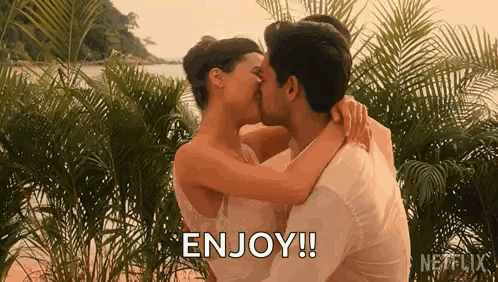 A Man And A Woman Are Kissing On A Beach . GIF