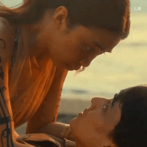 A Man And A Woman Are Kissing On The Beach With The Letters Lje On The Bottom GIF
