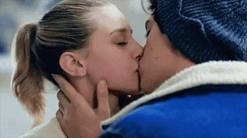 A Man And A Woman Are Kissing With Their Eyes Closed . The Woman Is Wearing A Ponytail . GIF