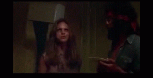 A Man And A Woman Are Laughing In A Dark Room . GIF