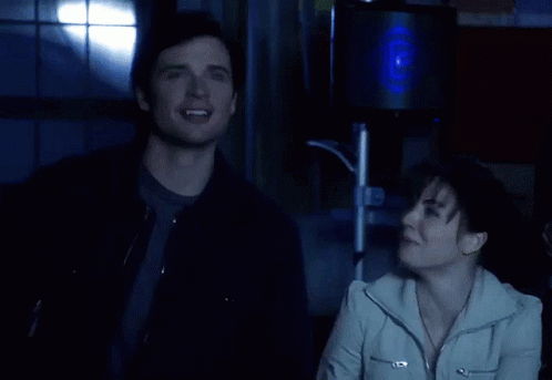 A Man And A Woman Are Laughing In Front Of A Speaker GIF