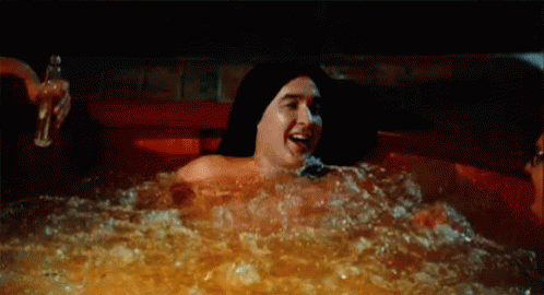 A Man And A Woman Are Laying In A Hot Tub . GIF