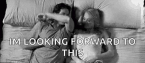 A Man And A Woman Are Laying In Bed Together And The Woman Is Covering The Man 'S Face . GIF