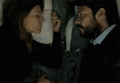 A Man And A Woman Are Laying Next To Each Other And Touching Their Noses GIF