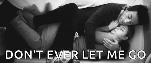 A Man And A Woman Are Laying On A Bed And Hugging . GIF