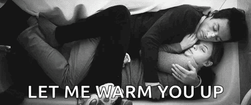 A Man And A Woman Are Laying On A Bed And Hugging . GIF