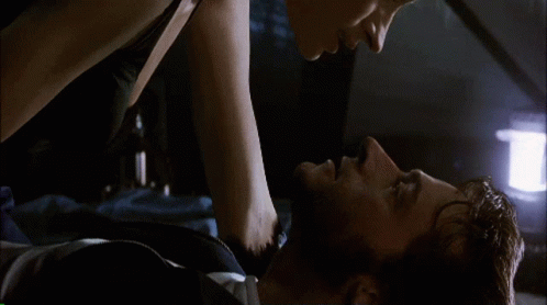 A Man And A Woman Are Laying On A Bed And Kissing GIF