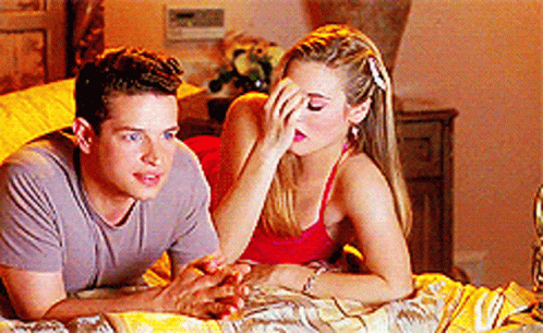 A Man And A Woman Are Laying On A Bed And The Woman Is Covering Her Face With Her Hand GIF