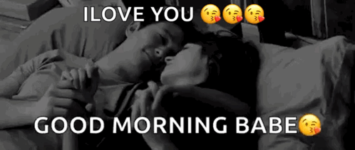 A Man And A Woman Are Laying On A Bed Holding Hands . GIF