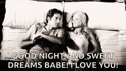 A Man And A Woman Are Laying On A Bed Together . GIF