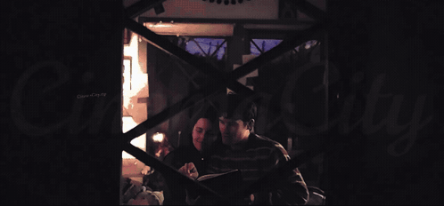 A Man And A Woman Are Laying On A Bed With A Canopy GIF