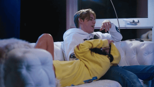 A Man And A Woman Are Laying On A Couch GIF