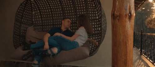 A Man And A Woman Are Laying On A Couch With The Sun Shining Through Them GIF