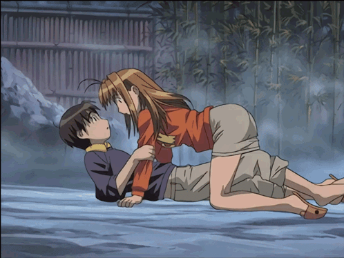 A Man And A Woman Are Laying On The Ground And The Woman Is Holding The Man 'S Arm GIF