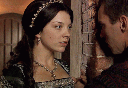 A Man And A Woman Are Leaning Against A Brick Wall Looking At Each Other GIF