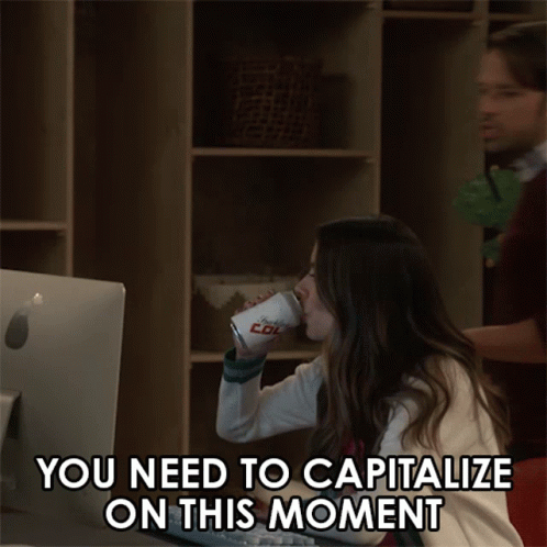 A Man And A Woman Are Looking At A Computer Screen With The Words You Need To Capitalize On This Moment GIF