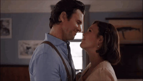 A Man And A Woman Are Looking At Each Other And Smiling GIF