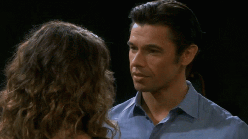 A Man And A Woman Are Looking At Each Other And The Man Is Wearing A Blue Shirt GIF
